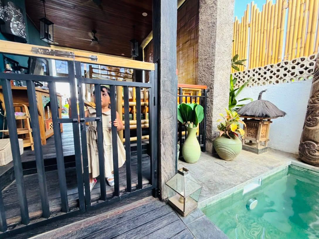 Ein Poolbereich mit Holzterrasse, Bambuszaun und einem Strohdach.