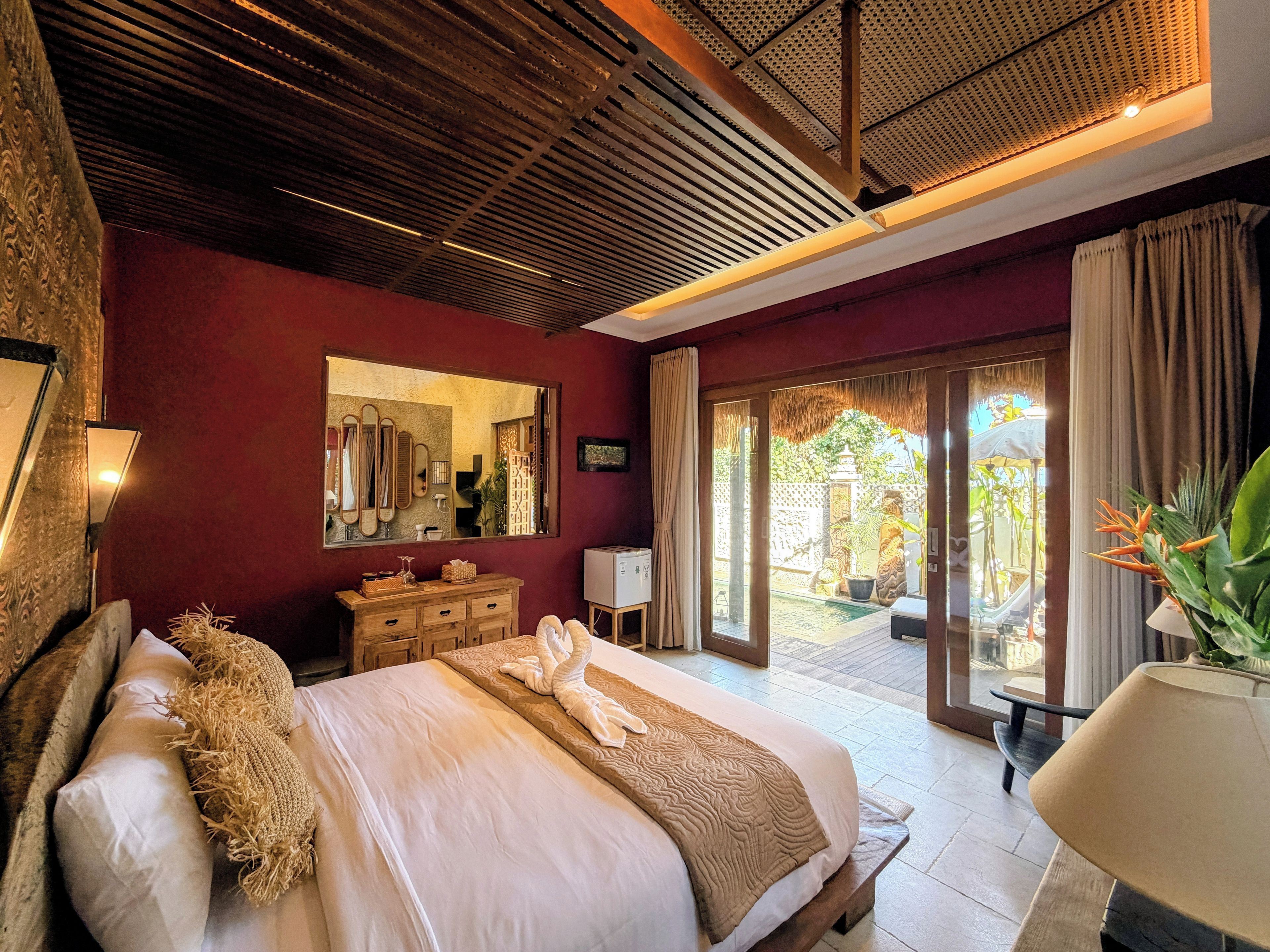 Un dormitorio con una cama grande, un aparador, un espejo y vistas al exterior.