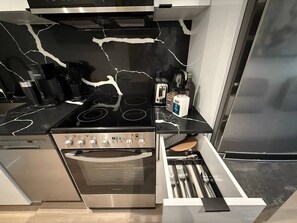 A modern kitchen with a black marble backsplash, stainless steel appliances, and a built-in oven. - Downtown like no other! (Montréal)