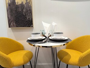 A small round table with two chairs, a painting on the wall, and a white wall. - Downtown like no other! (Montréal)