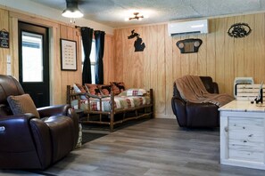 A room with a bed, two reclining chairs, a desk, and a window. - LakeEffectLodging-Cozy Cabin-ORV Trail Access (Luther)