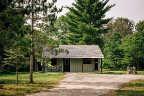 A small cabin with a gravel driveway, surrounded by trees. - LakeEffectLodging-Cozy Cabin-ORV Trail Access (Luther)