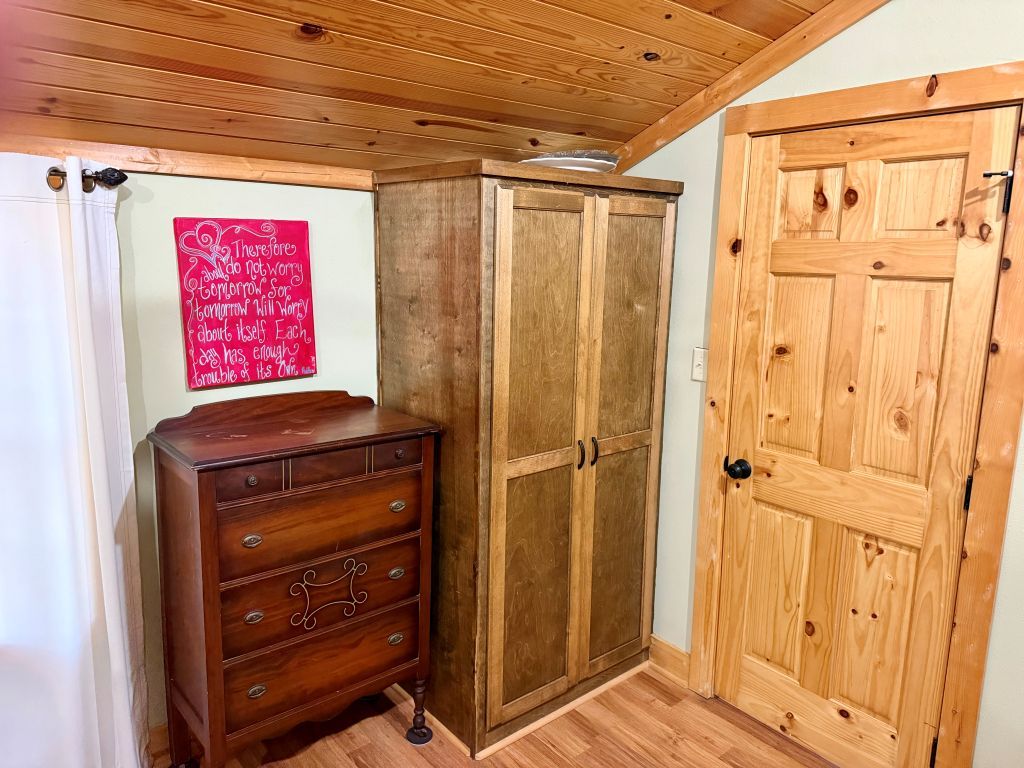 A wooden cabinet with a mirror, a wooden door, and a red sign on the wall.