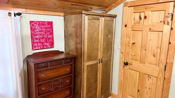 A wooden cabinet with a mirror, a wooden door, and a red sign on the wall.