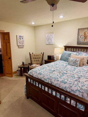 A bedroom with a wooden bed, a chair, a nightstand, and wall art.