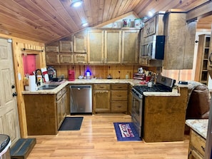 A kitchen with wooden cabinets, a stainless steel dishwasher, a gas stove, and a microwave.