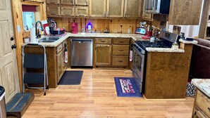 A kitchen with wooden cabinets, a dishwasher, a stove, and a microwave. - Charming 2-bedroom country house 15 minutes from Bryan with AC/Heat. (Bryan)