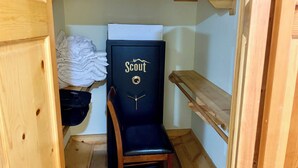 A small, narrow room with a black chair labeled 'Scout,' wooden shelves, and a white wall. - Charming 2-bedroom country house 15 minutes from Bryan with AC/Heat. (Bryan)