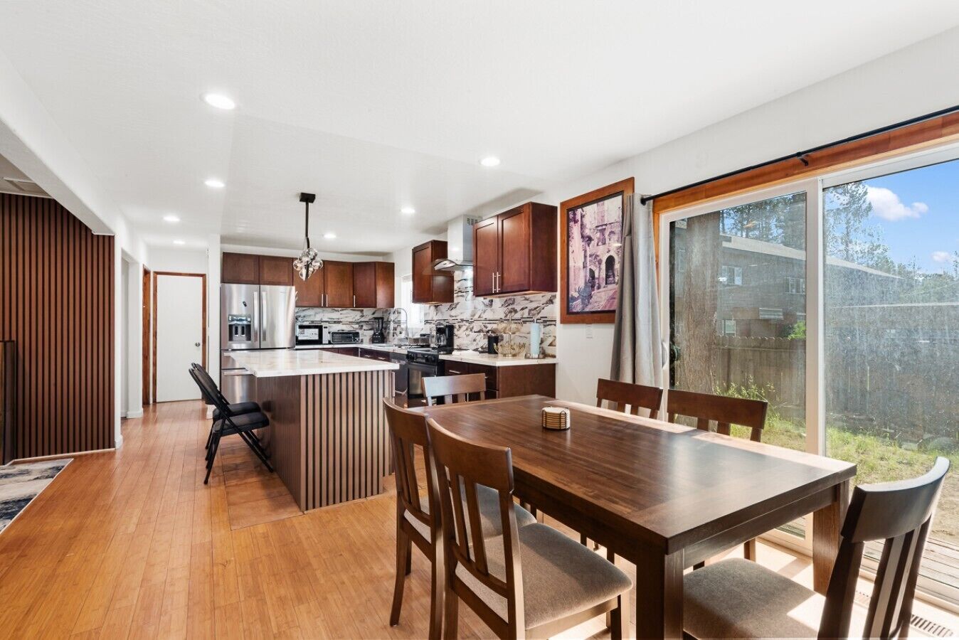 Una cocina moderna con una isla central, una mesa de comedor de madera y sillas.