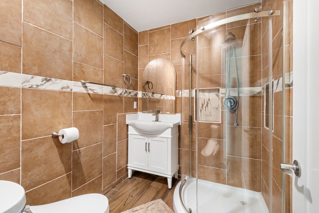 A bathroom with a glass-enclosed shower, a white sink, and a marble-tiled wall.