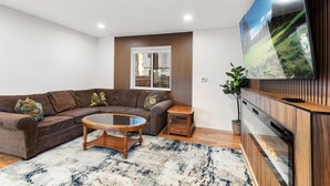 A modern living room with a sectional sofa, a coffee table, a TV, and a wooden cabinet. - Walk to Lake Tahoe | Sleeps 10 | EV Charger (South Lake Tahoe)