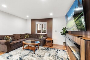 Ein modernes Wohnzimmer mit einer Eckcouch, einem Couchtisch, einem Fernseher und einer Holzkommode.
