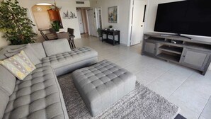 Een moderne woonkamer met een modulaire bank, een flatscreen televisie en een eethoek.