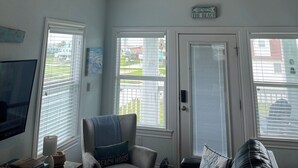 Ein Zimmer mit Deckenventilator, Fernseher, Stuhl und einer Tür mit einem Schild.