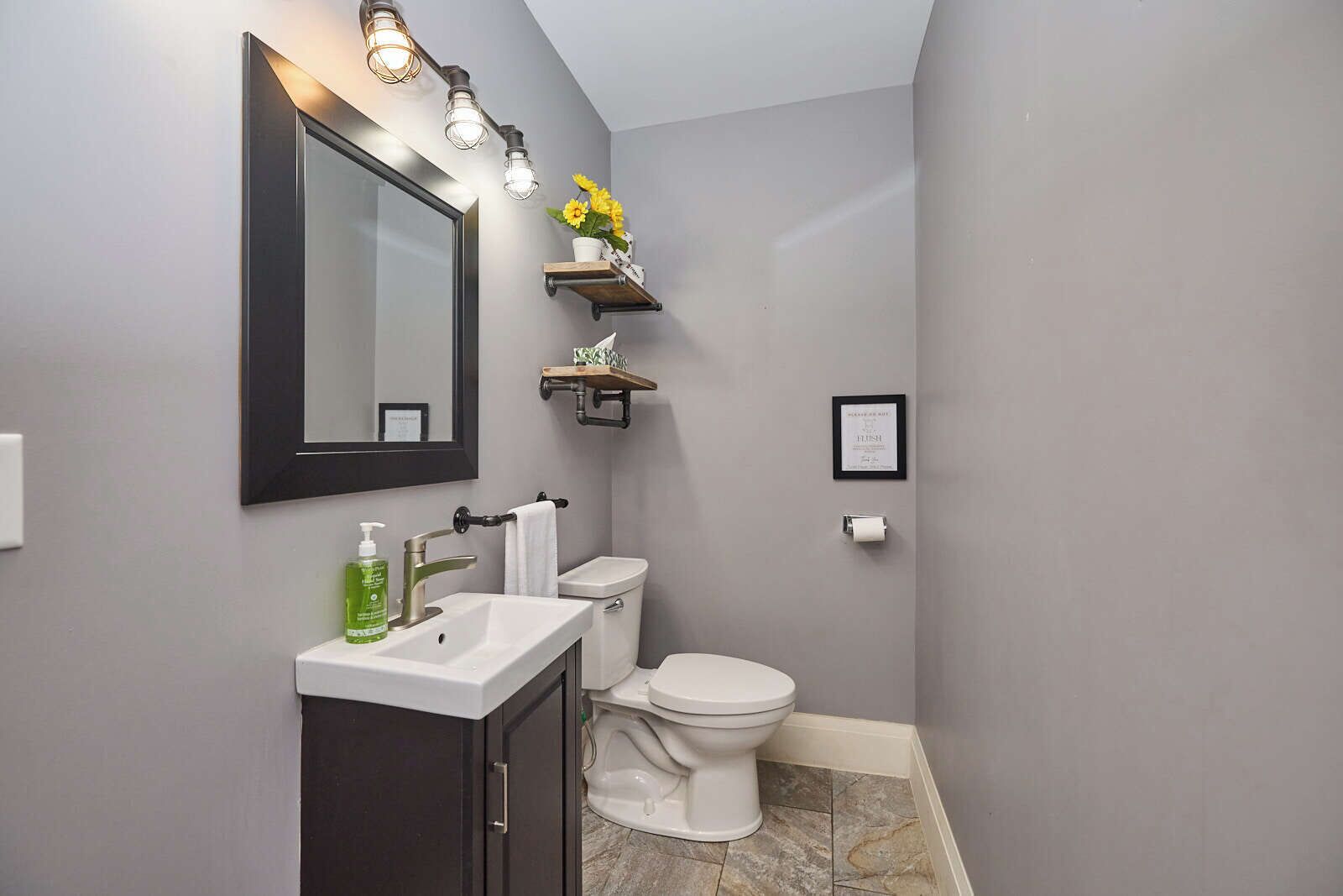 Une salle de bain avec un meuble-lavabo, des toilettes et un miroir avec éclairage.