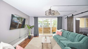 A modern living room with a green sofa, a coffee table, and a TV mounted on the wall.