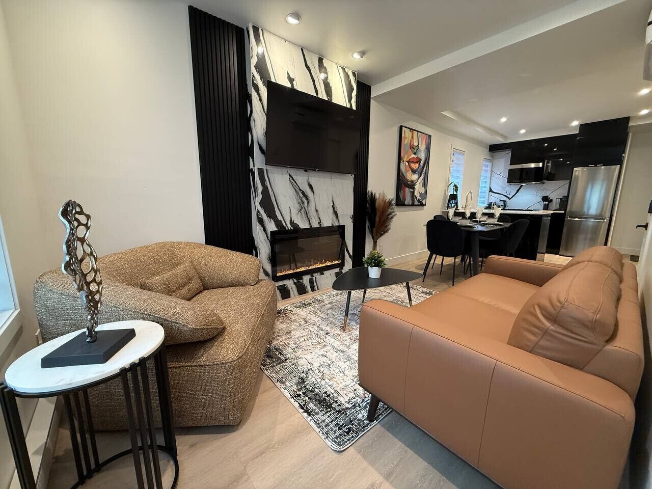 A modern living room with a fireplace, sofa, coffee table, and dining area.