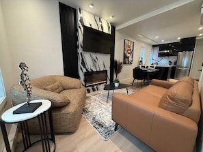 Uma sala de estar moderna com lareira, sofá, mesa de centro e espaço para refeições.