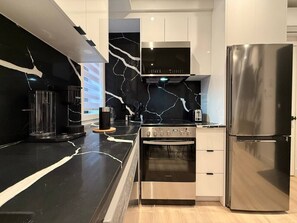 A modern kitchen with a black marble backsplash, stainless steel appliances, and light-colored cabinetry. - Le Style & Fashion 1BR Downtown Atwater Nightlife (Montréal)