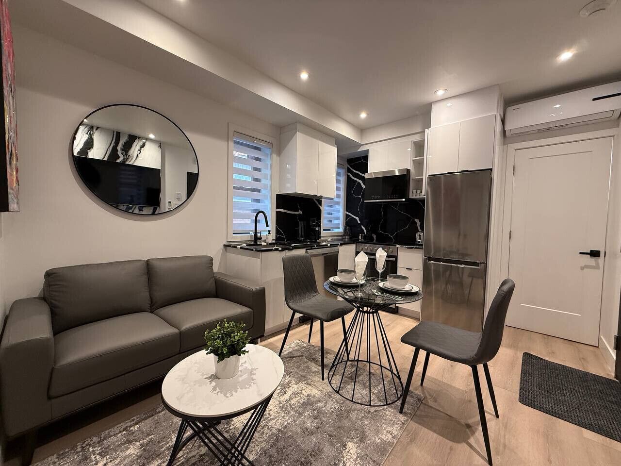 A modern living room with a sofa, a round coffee table, and a dining area with chairs.