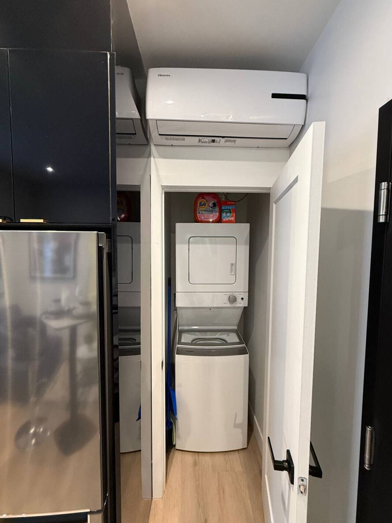 Een kleine keuken met een koelkast, een wasmachine en een airconditioner.