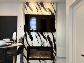 A modern kitchen with a marble backsplash, a built-in stove, and a dining area with a table and chairs. - High Fashion Downtown Living City Heart of MTL (Montréal)