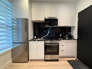 Eine moderne Küche mit Edelstahlgeräten, weißen Schränken und einer schwarzen Spritzschutzwand.