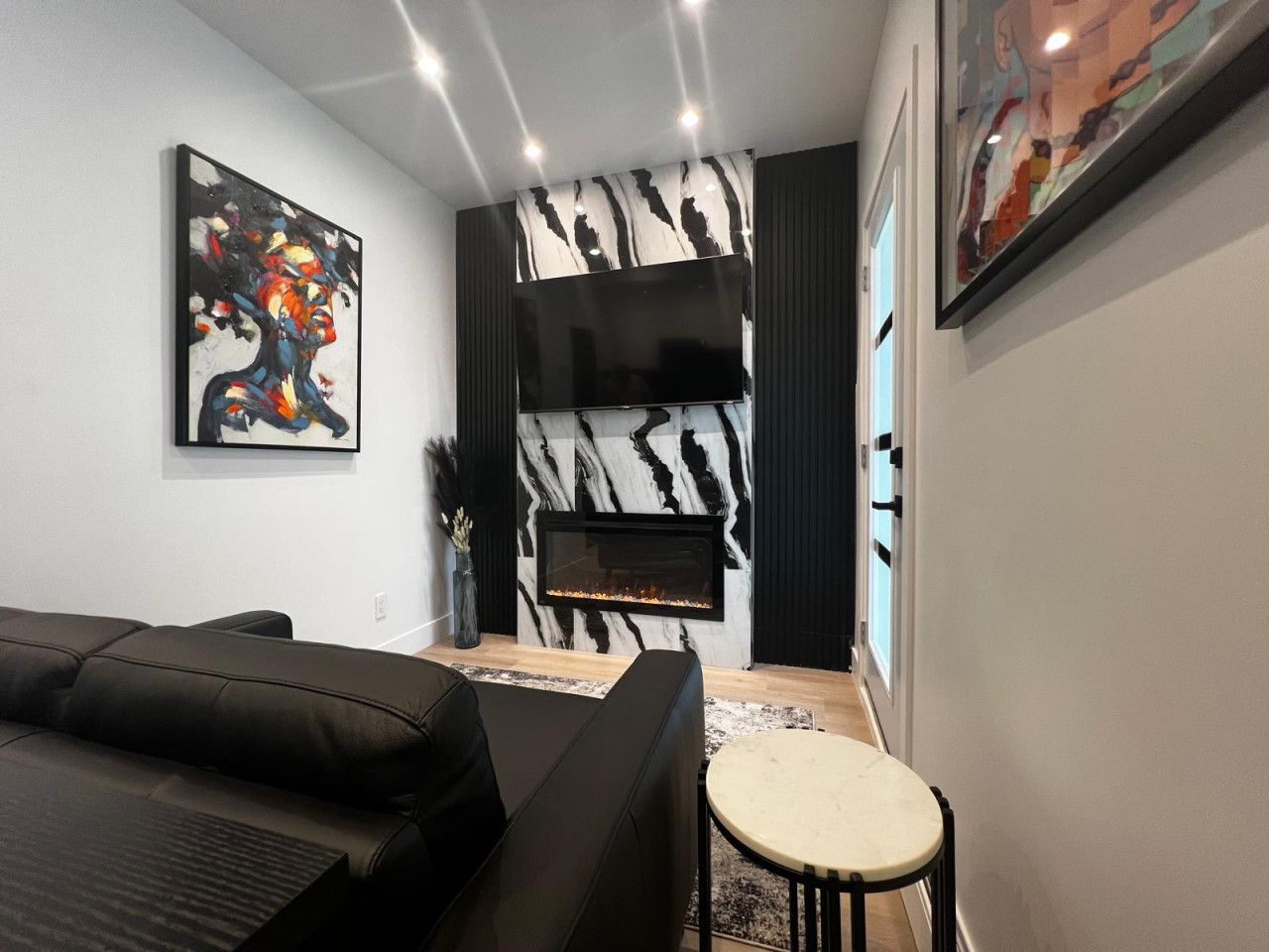 Un salon moderne avec un canapé, une cheminée et des œuvres d’art accrochées aux murs.