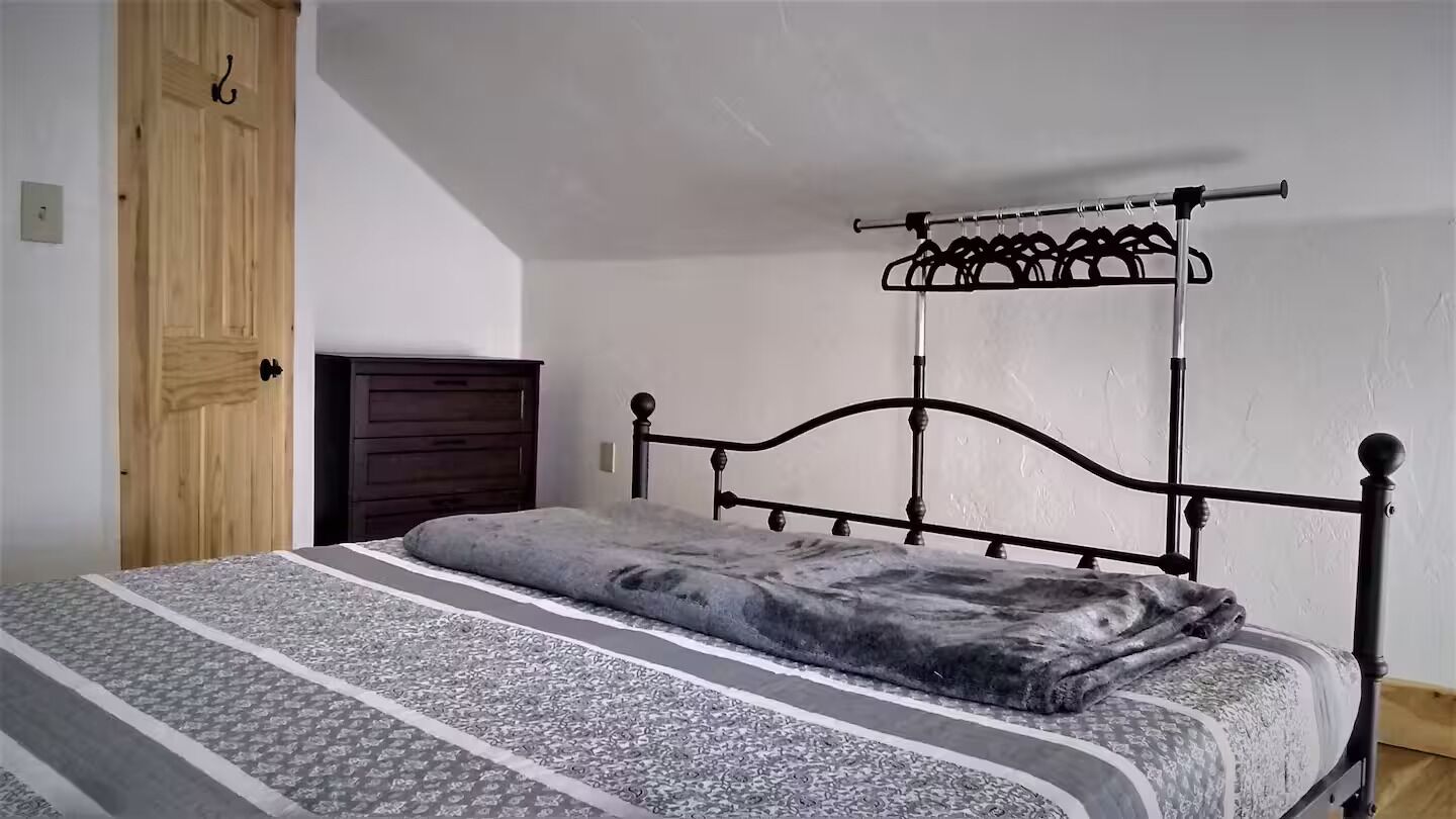 A bedroom with a bed, a wooden wardrobe, and a metal headboard.