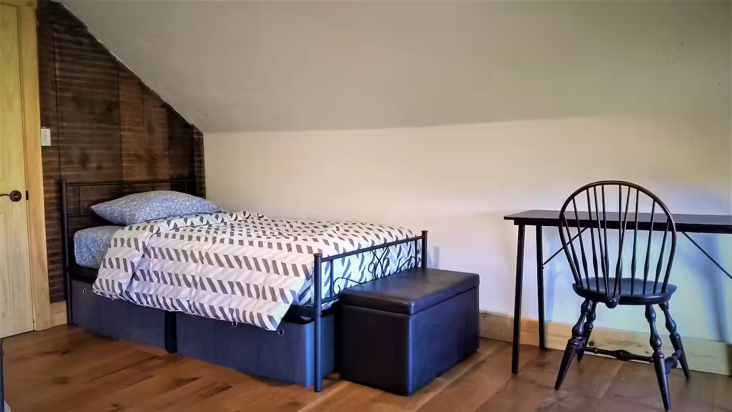 A bedroom with a bed, a desk, and a chair.