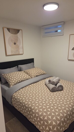 Ein Schlafzimmer mit einem Bett, Kissen, einem Kopfteil und zwei gerahmten Kunstwerken an den Wänden.