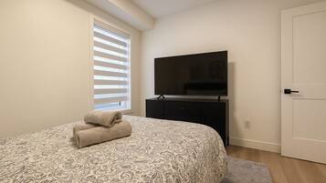 Een slaapkamer met een bed, een televisie, een dressoir en een deur.