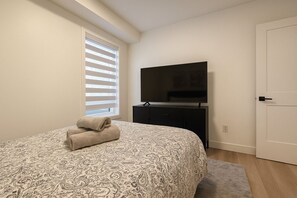 Une chambre à coucher avec un lit, une télévision, une commode et une porte.