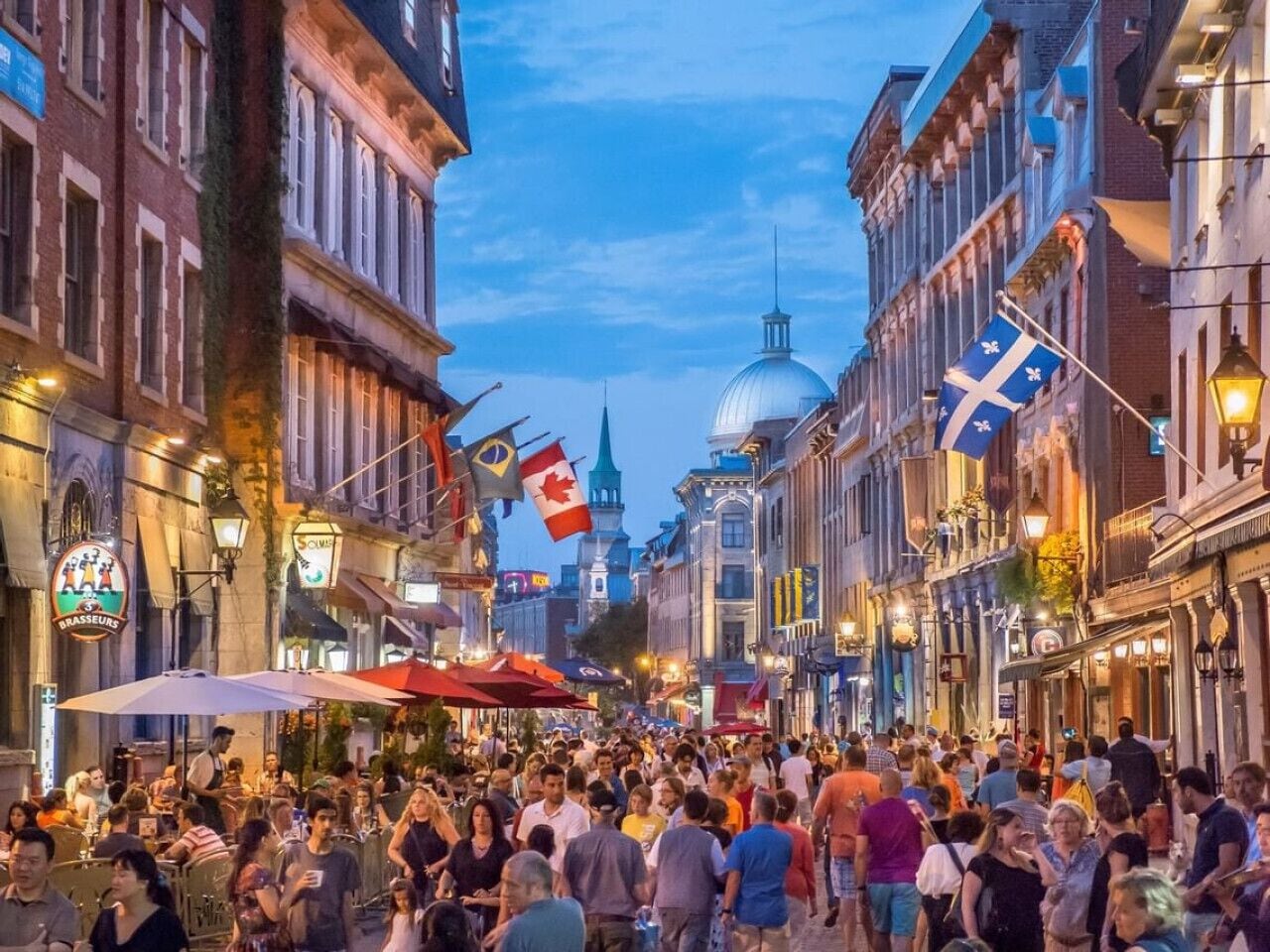 Une rue animée bordée d’immeubles, de drapeaux et de terrasses.