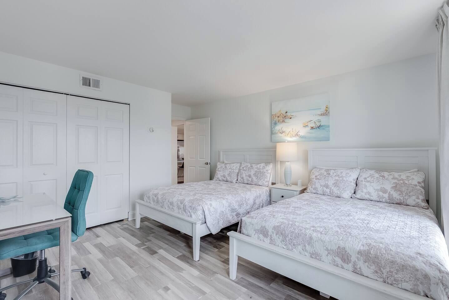 A bedroom with two beds, a desk, and a chair.