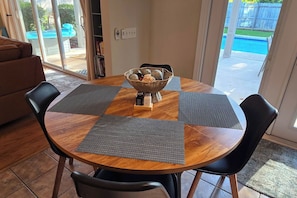 Una mesa de comedor redonda de madera con sillas negras, una cesta tejida con pan y saleros y pimenteros.