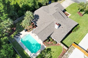 Ein Wohnhaus mit Schwimmbad, einer überdachten Terrasse und einem gepflegten Rasen.