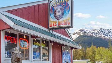 A red building with a sign for Silver Tip Grill and Live Music, a bear statue outside, and a mountain in the background.