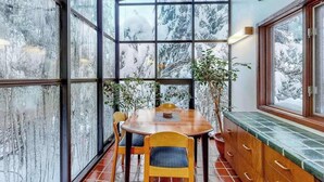 Ein Zimmer mit Glasdecke, einem Holzesstisch, Stühlen und einer Bank mit Schubladen.
