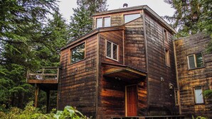 Eine rustikale Holzjagdhaus mit Balkon, einer Haustür und einer Treppe, die zum Eingang führt.