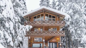 Un lodge in legno a più piani con un balcone, circondato da alberi innevati.