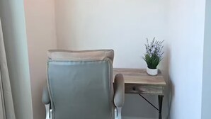 Oficina en esquina con una silla de oficina gris, un escritorio de madera y un cuadro colgado en la pared.