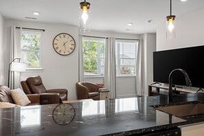 A modern kitchen with a black countertop, a built-in sink, and pendant lighting.