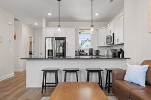 Una cocina moderna con una isla central, taburetes de bar y una mesa de comedor.
