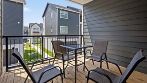 Un balcón con mesa y sillas, con vista a una zona residencial.