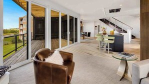 Een ruime woonkamer met balkon, trap en moderne keuken.
