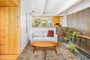 Ein modernes Interieur mit einer Steinwand, einem Sofa, einem Holztisch und einer Holztür.