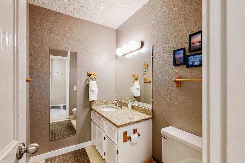 Une salle de bain équipée d’un lavabo, d’un miroir, de toilettes et d’un porte-serviettes.