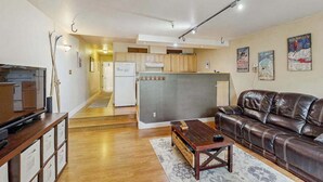A compact living space with a kitchen, a sofa, a TV, and a dining table. - North 413 | True Ski-In/Out | Gas Fireplace (Girdwood)