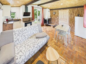Un'accogliente zona giorno con divano, tavolo da pranzo e angolo cottura, inclusi televisore e orologio.